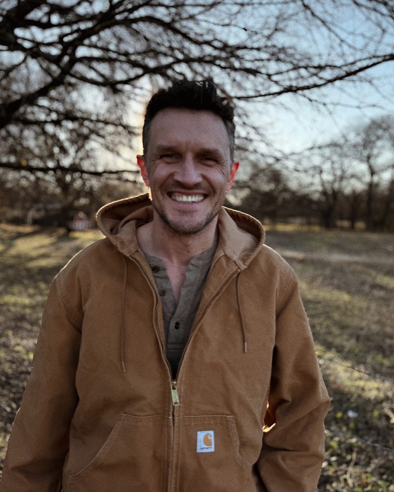 Alex Bond, founder of Bond Bookkeeping & Advisory, smiling outdoors in a canvas work jacket
