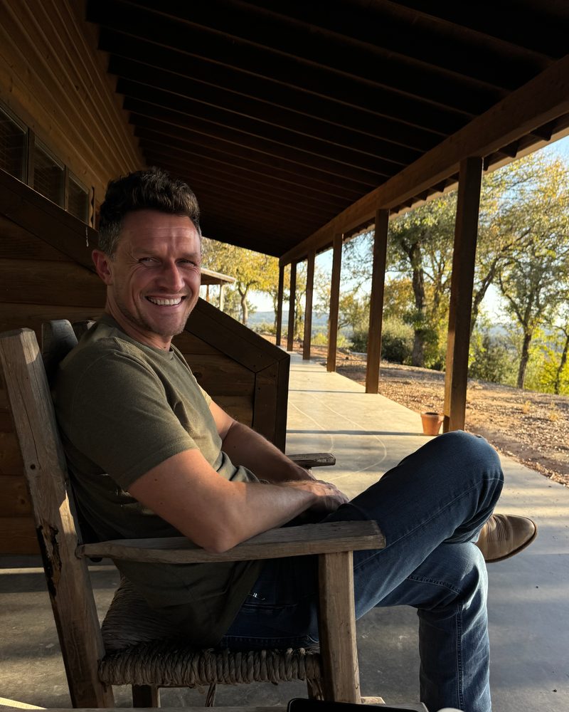 Alex Bond relaxing in a rocking chair on a covered porch