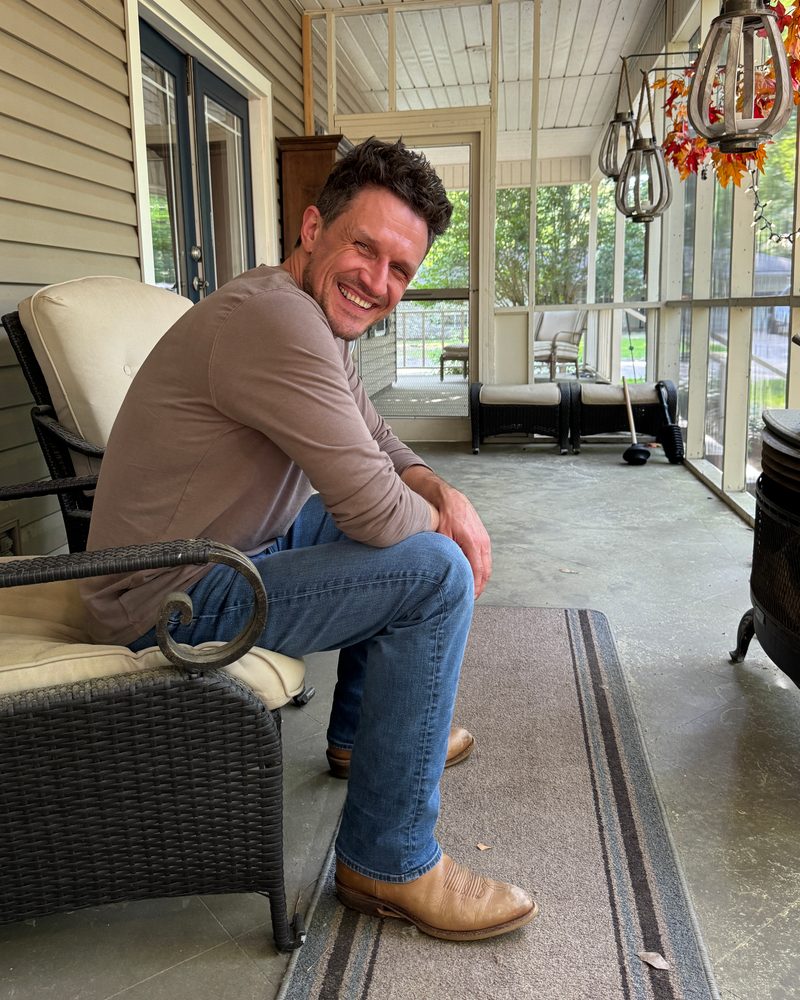 Alex Bond laughing on a screened-in porch